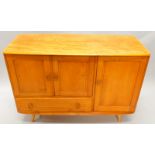 An Ercol light elm sideboard, with a shaped top above a single door, flanked by a pair of panelled