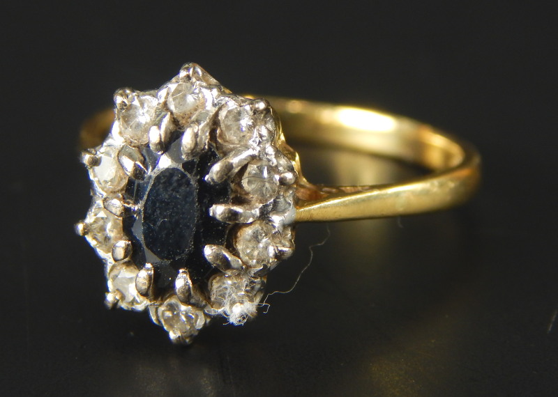 A floral cluster dress ring, with central sapphire, surrounded by ten tiny diamonds, yellow metal,