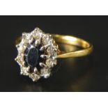 A floral cluster dress ring, with central sapphire, surrounded by ten tiny diamonds, yellow metal,