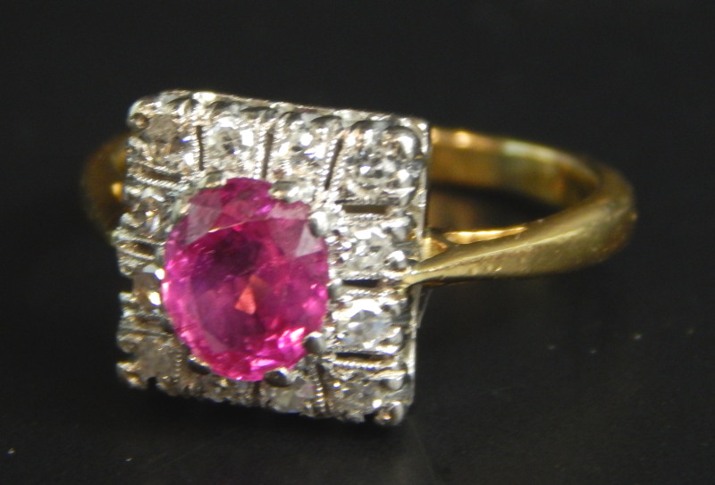 An Art Deco dress ring, set with central ruby, surrounded by tiny diamonds, on yellow metal band,