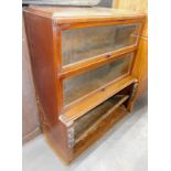 A 1920's oak Globe Wernicke type bookcase, with three sliding glazed doors, the base with carved and