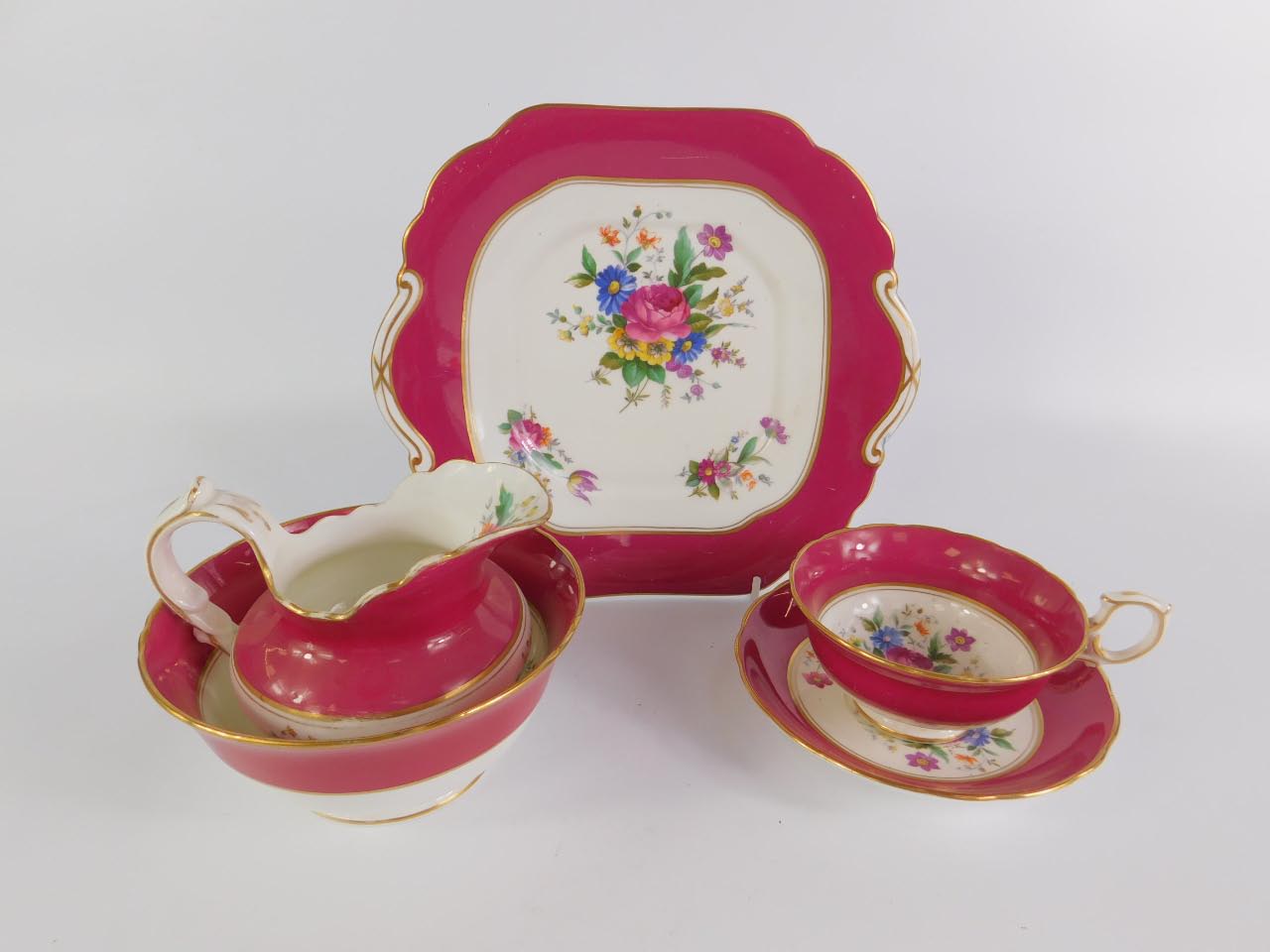 An early 20thC porcelain tea service printed with floral sprays, within a burgundy border,