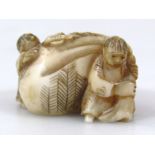 A Japanese carved ivory netsuke, of two figures hauling a very large sack, 1.7cm long.(Taisho period