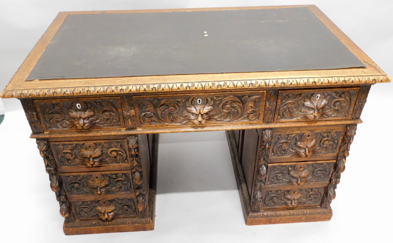 A Victorian oak pedestal desk, carved overall with foliate scrolls, masks, etc, the rectangular