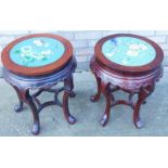 A near pair of Chinese hardwood urn stands, each with a cloisonné panel inset to the top, decorated