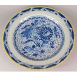 A late 18th/early 19thC Delft charger, decorated in blue centrally with flowers within a band of