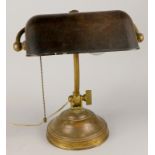 An early 20thC brass adjustable desk lamp, with bronzed shade, beaded on/off pull and iron filled