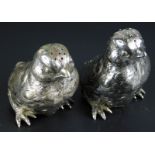 A near pair of novelty silver coloured metal pepper pots, each modelled in the form of a chick,