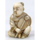 A Japanese carved ivory netsuke, of a seated baby boy holding a fan, 4.1cm long.(Taisho period