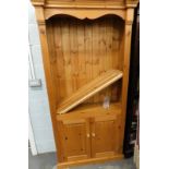 A stripped and lightly polished Ducal style pine open bookcase, above double cupboard on block base