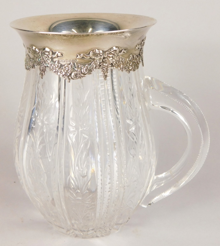 A Tiffany cut glass jug, decorated with bands of flowers, leaves, etc., with silver mount cast