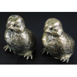 A near pair of silver coloured metal novelty pepper pots, each modelled in the form of a chick,