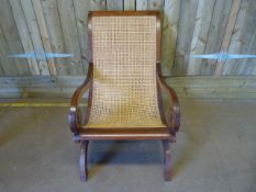 A cane seated chair on mahogany frame with scroll arms