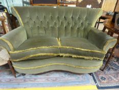 A small green upholstered button back shaped sofa