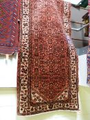 A large red ground persian runner - with an all over design