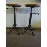 A pair of wrought iron machinist style stools with wooden seats