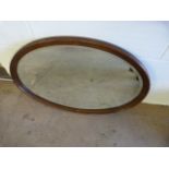 An oval oak framed mirror