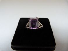 A Silver Ring set with an Emerald Cut Lilac coloured CZ 10mm x 8.2mm with 2 small white CZ's set