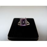 A Silver Ring set with an Emerald Cut Lilac coloured CZ 10mm x 8.2mm with 2 small white CZ's set