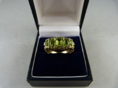 A 9ct Yellow Gold ring set with oval Peridot stones and eight diamond chips, table facets a little