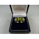 A 9ct Yellow Gold ring set with oval Peridot stones and eight diamond chips, table facets a little