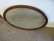 An oval oak framed mirror