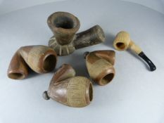 Three various sized matching African pottery pipe bowls and two wooden pipes one tribal with remains