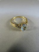 9ct gold ring set with possibly aqua marine oval in shape and with diamond to each shoulder