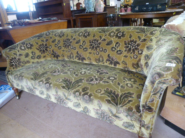 Low two seater floral upholstered sofa on metal castors