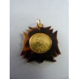 An 1887 Victorian Half Sovereign in good condition mounted on Tortoise shell surround to form a