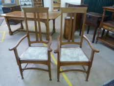 Pair of Arts and Crafts golden oak high slatted back carver chairs with curved arms and foliate