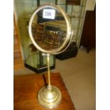 An early 20th century brass shaving mirror having a double sided swivel mirror raised on a