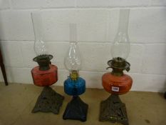 Three 'British Made' oil lamps with coloured glass wells. 1 blue glass, and two cranberry glass