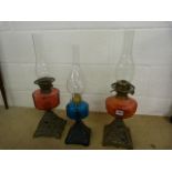 Three 'British Made' oil lamps with coloured glass wells. 1 blue glass, and two cranberry glass