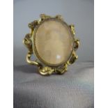 Pinchbeck mourning brooch/photo frame in the Nouveau style. Wave decoration round an ovular frame,