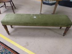 Long low green upholstered window seat on Sheraton style legs