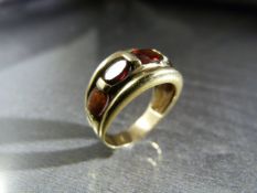 Unmarked Gold ring approx 11mm wide and set with 5 graduated Oval Garnet stones. Size approx UK -