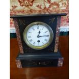 Small slate marble clock inlaid with marble. Enamelled dial with Roman Numerals.