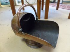 A copper coal scuttle, 19th century, with bale handle and supported upon a circular foot.