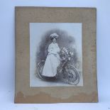 An early black and white photograph of a lady on a bicycle.