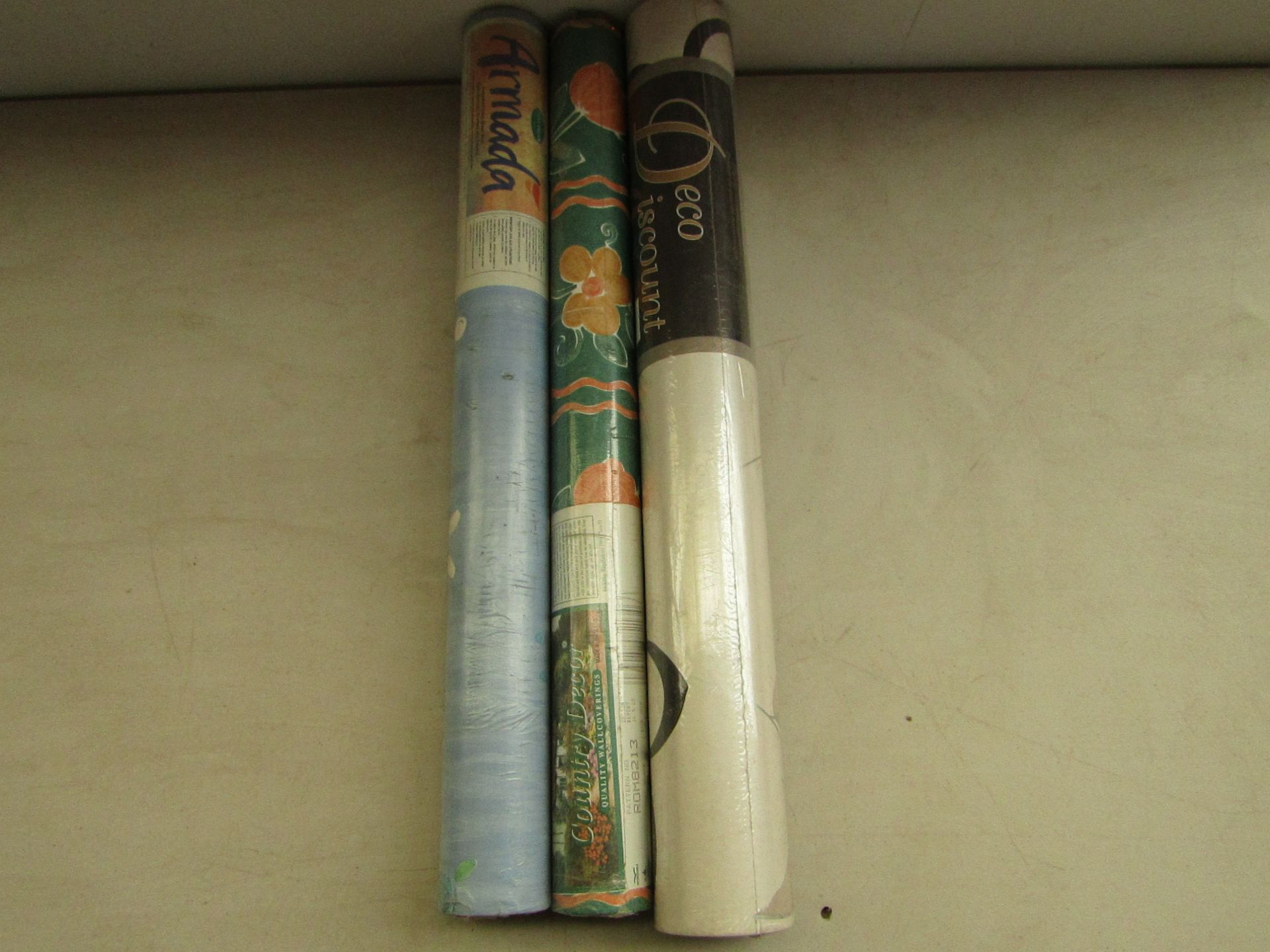 Box of 11x various rolls of wallpaper with brands such as Country decor and Armada.