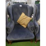 Blue velour-type upholstered wing back chair on carved legs & pad feet