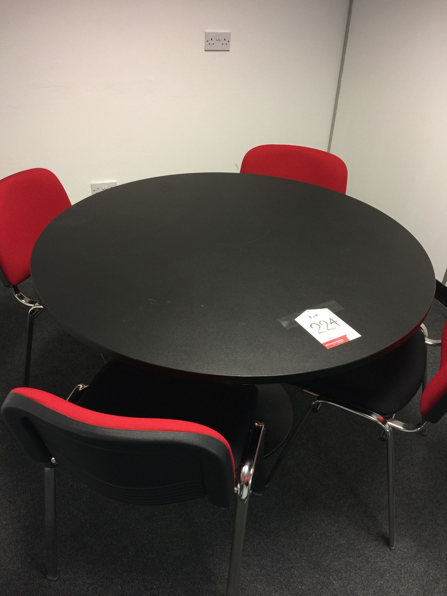 Circular conference table and four red upholstered chairs