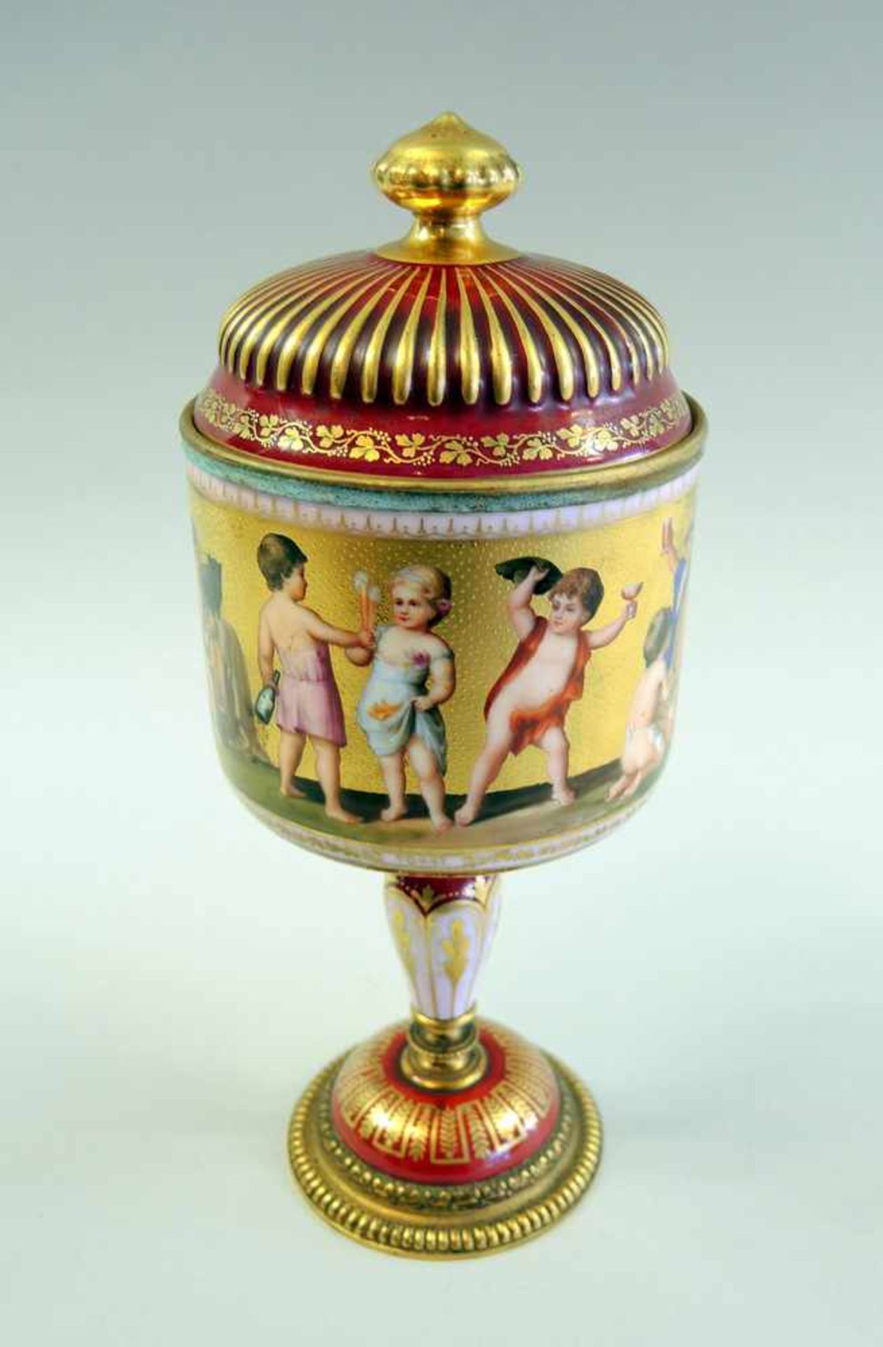 Deckelpokal mit Putti Porzellan mit Messingmontur. Auf goldenem Grund umlaufender Dekor mit Putti