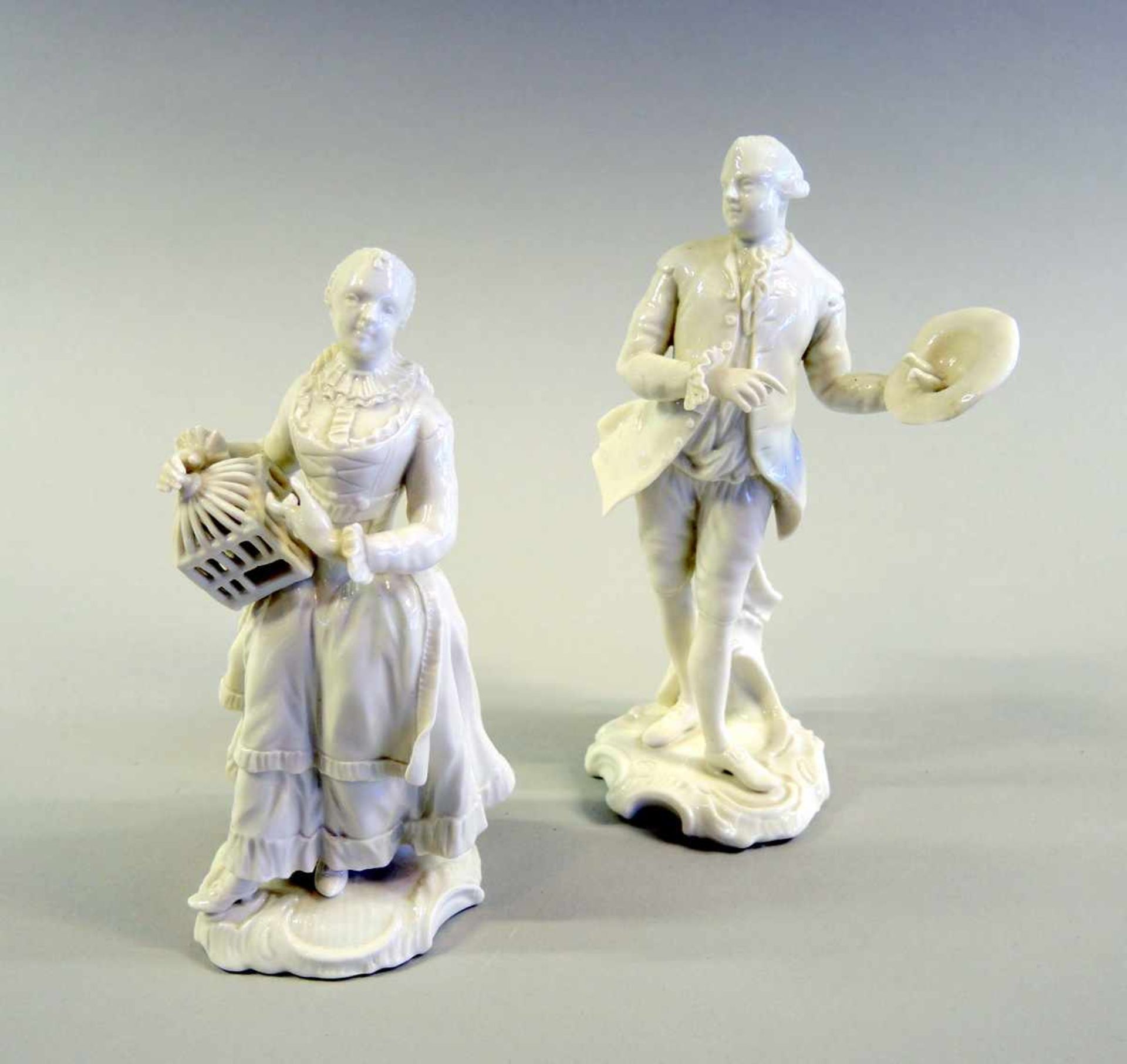 Paar Nymphenburgfiguren Weißporzellan. Galanter Herr mit Hut und Dame mit Vogelkäfig. Modell