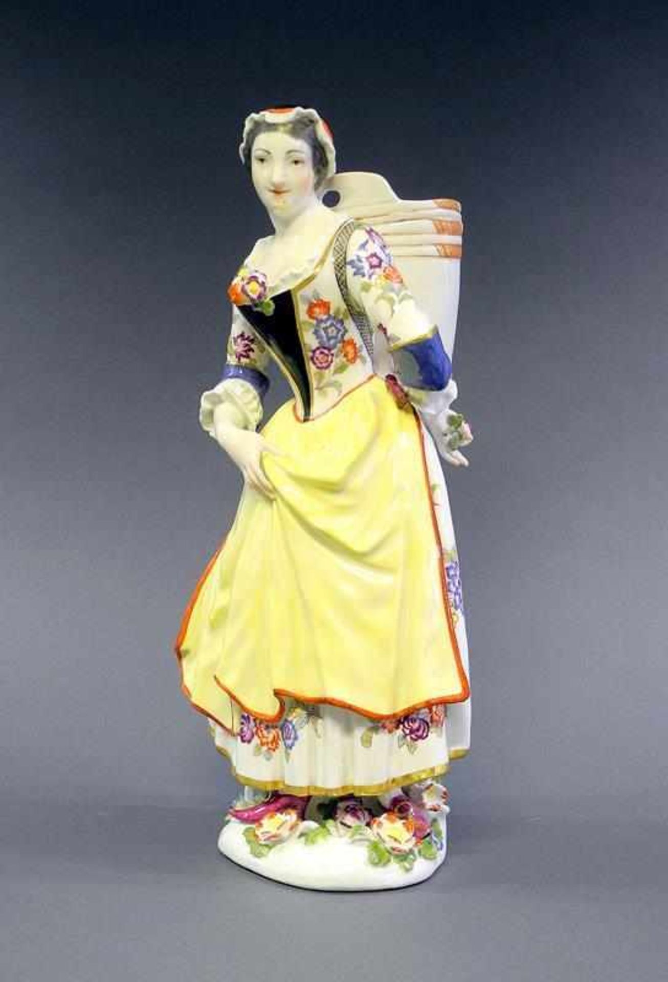 Meissen Figur, Magd mit Kiepe Porzellan, polychrom bemalt. Plastische Blumen an Sockel und Figur.