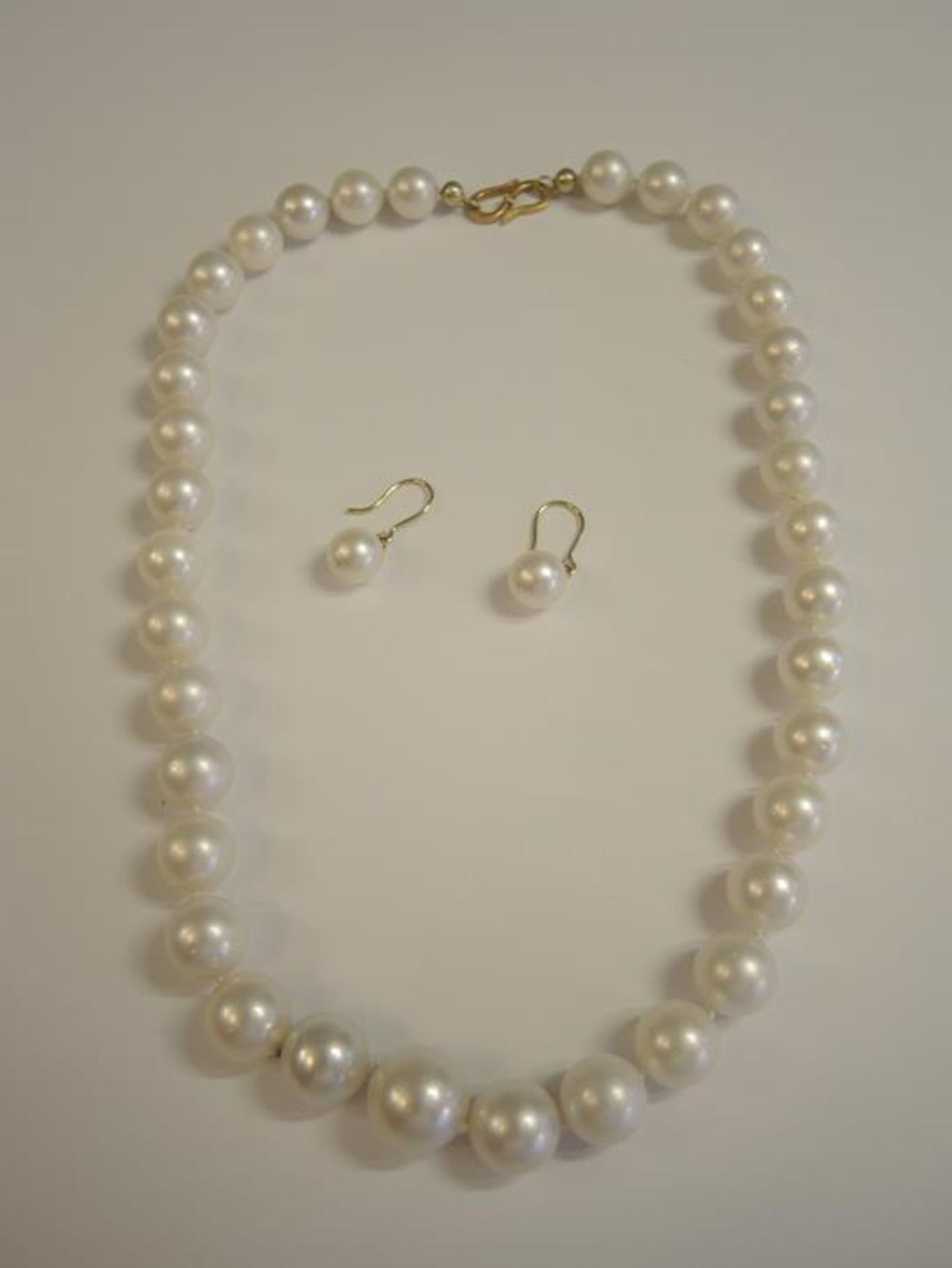 Große Perlenkette Mit Hackenverschluss und kleinen Diamanten besetzt, dazu die passenden Ohrringe.