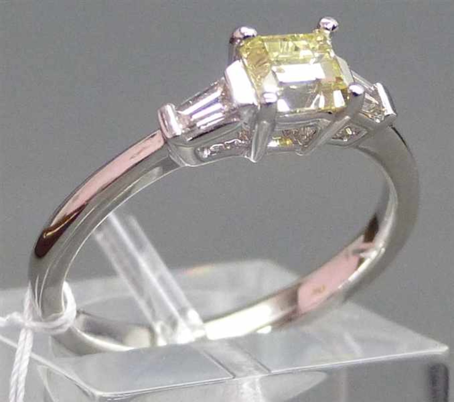 Damenring 18 kt. Weißgold, 1 Diamantbaguette 0,616 ct., light yellow, si, 2 Diamanten im