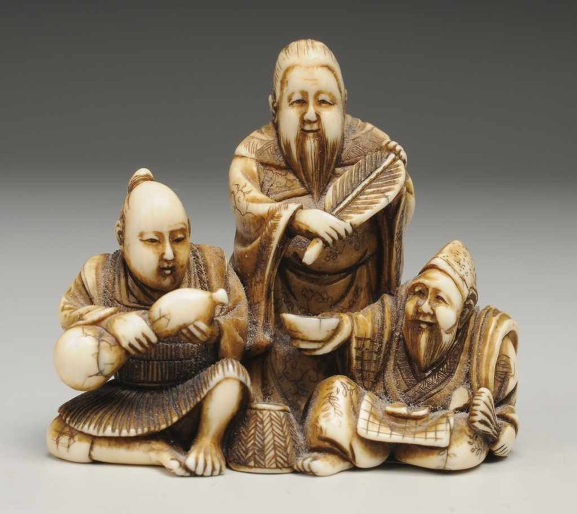 Netsuke Elfenbein. Feine filigran gearbeitete figürliche Darstellung dreier Männer, einer im