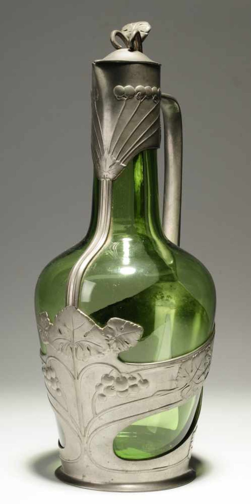 Jugendstil-Karaffe Grünes Glas. Formgeblasen. Zinnmontierung mit scharniertem Deckel. Reliefdekor